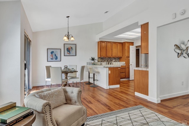 63 Brighton Dr, Vallejo, CA 94591 - kitchen with tile counters, a peninsula, brown cabinetry, a kitchen breakfast bar, and a chandelier