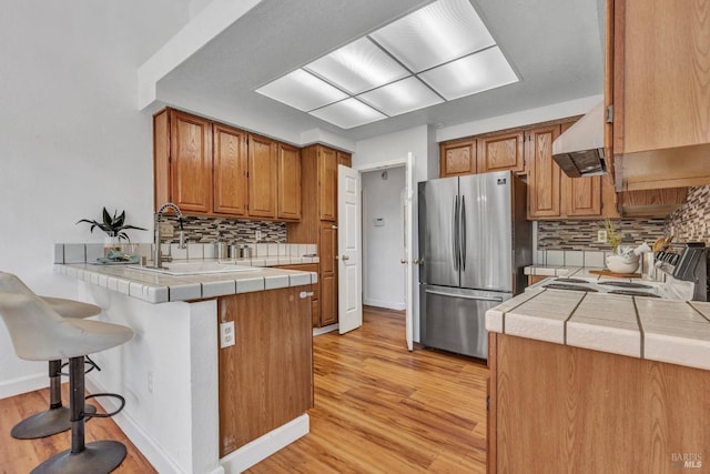 63 Brighton Dr, Vallejo, CA 94591 - kitchen with freestanding refrigerator, under cabinet range hood, a peninsula, light wood-type flooring, and tile counters