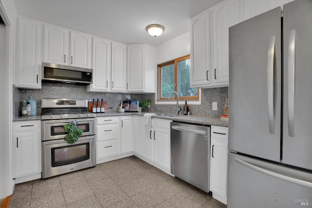 kitchen featuring appliances with stainless steel finishes, a sink, backsplash, and granite floors