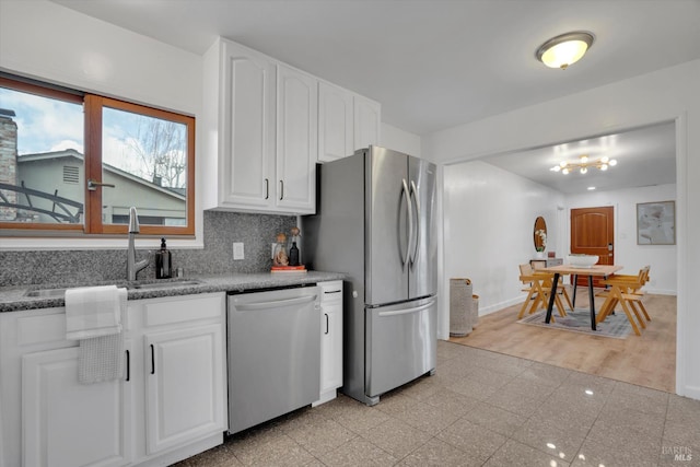 kitchen with appliances with stainless steel finishes, a sink, granite tiled floors, white cabinets, and tasteful backsplash