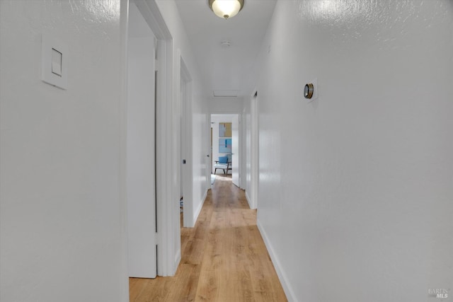 hallway featuring light wood-style floors and baseboards