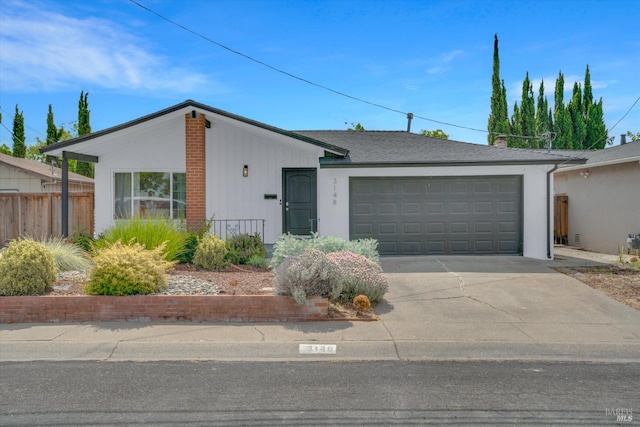 view of front of property featuring an attached garage, concrete driveway, and fence