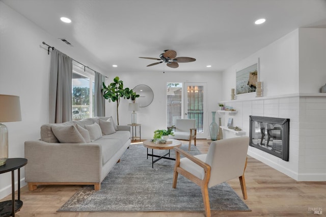 living area with wood finished floors, ceiling fan, recessed lighting, and a tiled fireplace