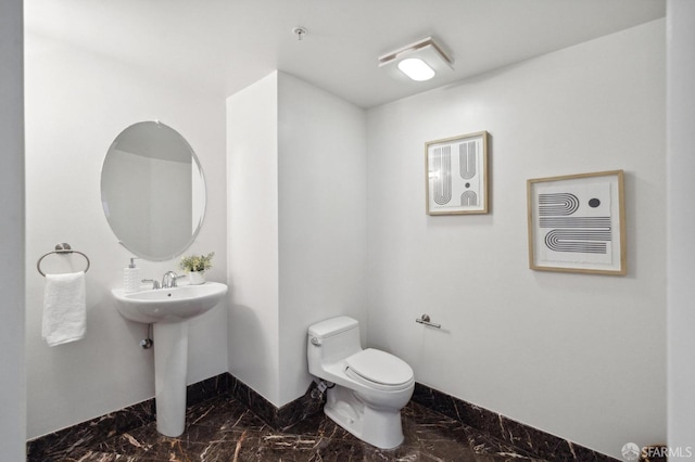 1452 Bush St Unit 9, San Francisco, CA 94109 - half bathroom featuring marble look tiles, baseboards, toilet, and a sink