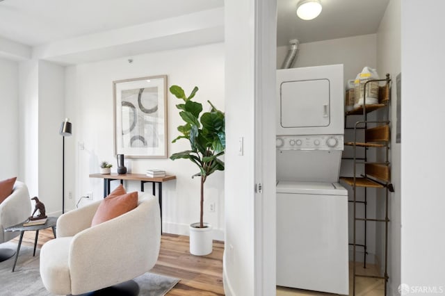 clothes washing area with estacked washer and dryer, light wood finished floors, and baseboards