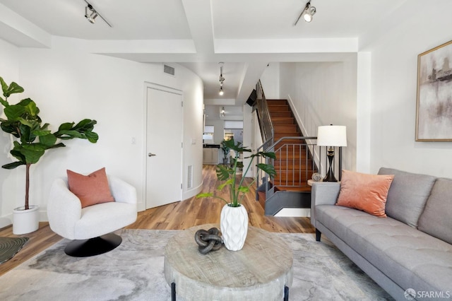 living area featuring wood finished floors, stairway, and track lighting