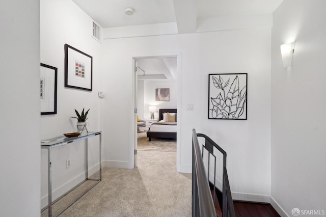 hallway with baseboards, carpet flooring, and beam ceiling
