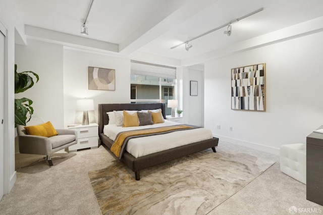 carpeted bedroom with track lighting and baseboards
