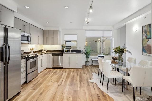 1452 Bush St Unit 9, San Francisco, CA 94109 - kitchen with stainless steel appliances, dark countertops, light wood finished floors, gray cabinets, and healthy amount of natural light