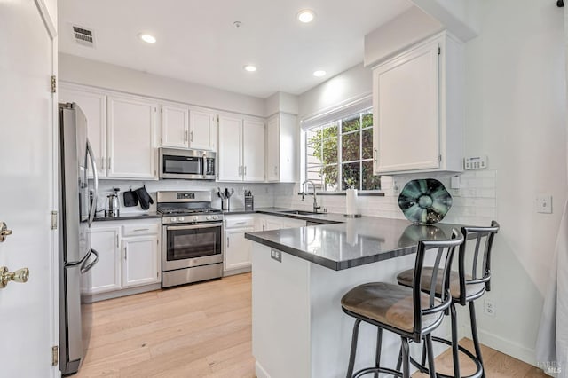 2064 Easton Dr, Petaluma, CA 94952 - kitchen featuring stainless steel appliances, a peninsula, a sink, light wood-style flooring, and recessed lighting