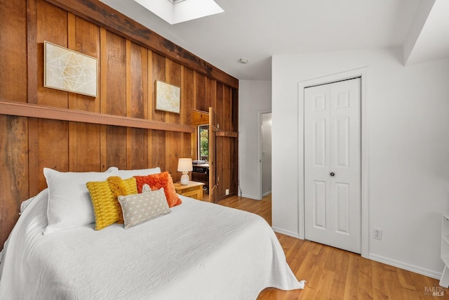 16635 Center Way, Guerneville, CA 95446 - bedroom with wood walls, a skylight, a closet, baseboards, and light wood-style floors