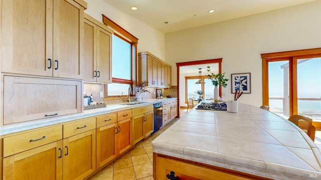 kitchen with black dishwasher, a sink, plenty of natural light, tile countertops, and recessed lighting