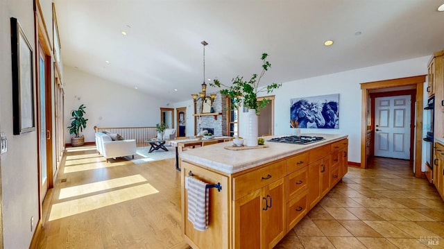 kitchen with lofted ceiling, gas cooktop, light countertops, oven, and open floor plan