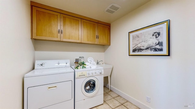clothes washing area with separate washer and dryer, cabinet space, light tile patterned floors, and baseboards