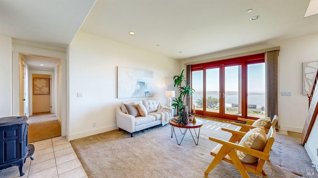 tiled living room featuring carpet, a wood stove, recessed lighting, baseboards, and a water view
