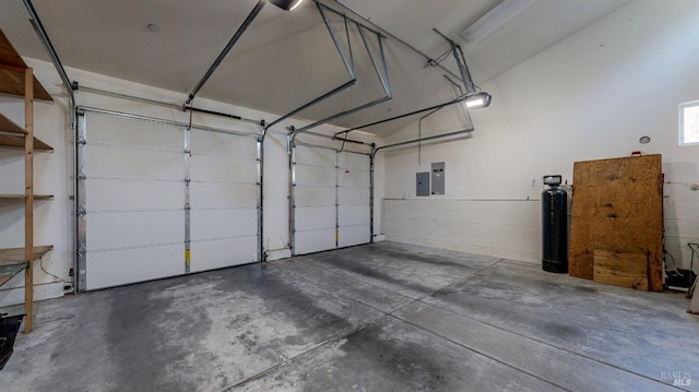 garage with concrete block wall, electric panel, and a garage door opener