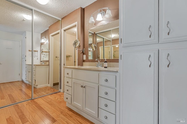 full bath with a textured ceiling, hardwood / wood-style floors, and vanity