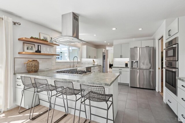 249 Los Palos St, Sonoma, CA 95476 - kitchen featuring stainless steel appliances, island exhaust hood, a peninsula, a kitchen bar, and backsplash