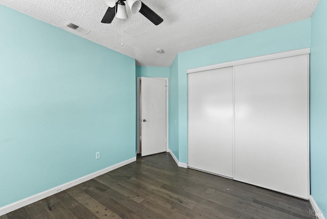 unfurnished bedroom with dark wood-style flooring, baseboards, a closet, a textured ceiling, and a ceiling fan