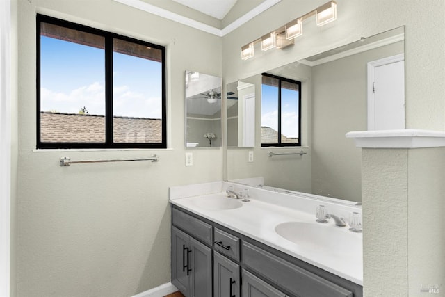 bathroom with double vanity, a textured wall, and ornamental molding