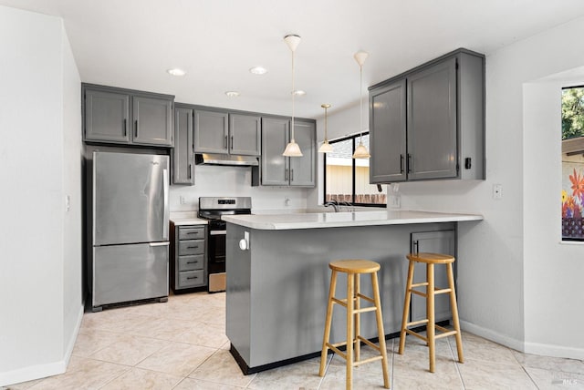 kitchen featuring appliances with stainless steel finishes, under cabinet range hood, baseboards, light countertops, and a peninsula