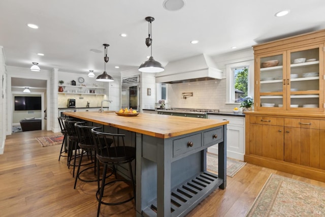 2170 Vineyard Rd, Novato, CA 94947 - kitchen with wooden counters, stainless steel appliances, tasteful backsplash, premium range hood, and light wood-type flooring