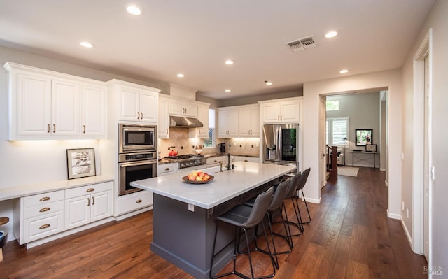 4152 Casper Way, Napa, CA 94558 - kitchen featuring appliances with stainless steel finishes, under cabinet range hood, white cabinetry, a kitchen bar, and dark wood finished floors