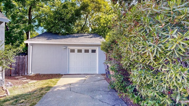 detached garage featuring fence and driveway