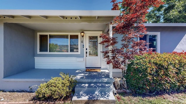 property entrance featuring stucco siding and covered porch