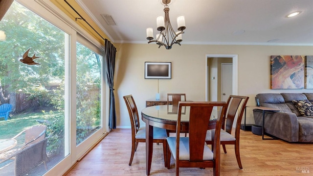 dining area with a chandelier, light wood finished floors, ornamental molding, and baseboards