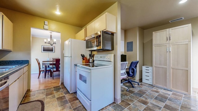 kitchen with appliances with stainless steel finishes, dark stone finish flooring, a chandelier, dark countertops, and a desk