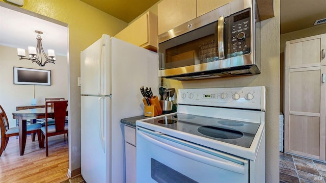 kitchen featuring white appliances, a chandelier, dark countertops, pendant lighting, and light wood-style floors
