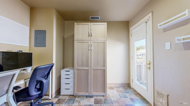 office featuring electric panel, baseboards, and stone finish floors