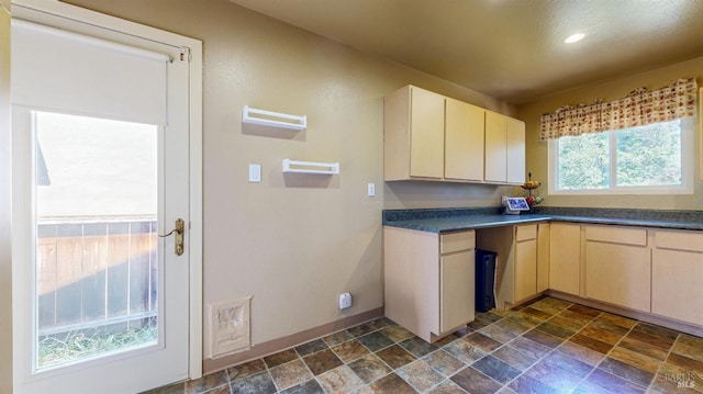 kitchen featuring dark stone finish floors, baseboards, dark countertops, recessed lighting, and light brown cabinetry