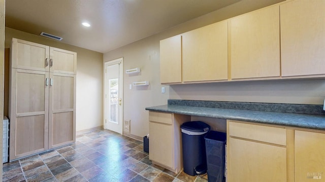 kitchen featuring stone finish flooring, dark countertops, light brown cabinets, baseboards, and recessed lighting