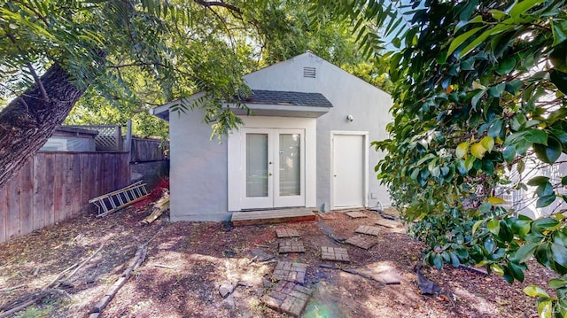view of outdoor structure featuring fence, an outbuilding, and french doors