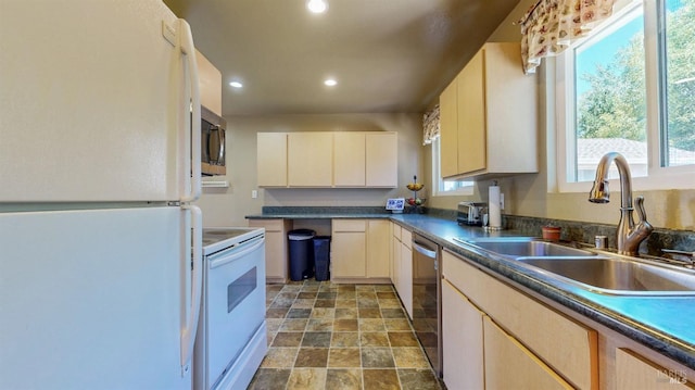 kitchen featuring appliances with stainless steel finishes, a sink, recessed lighting, stone finish flooring, and dark countertops