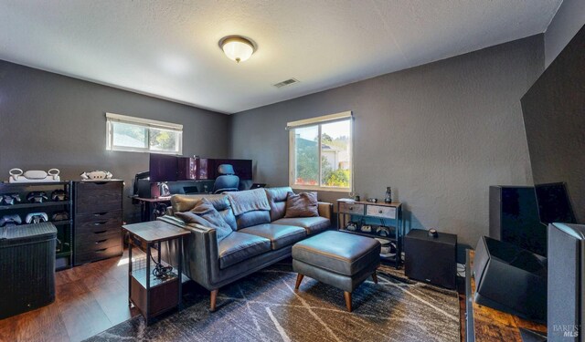 living room with an office area, wood finished floors, and a textured wall