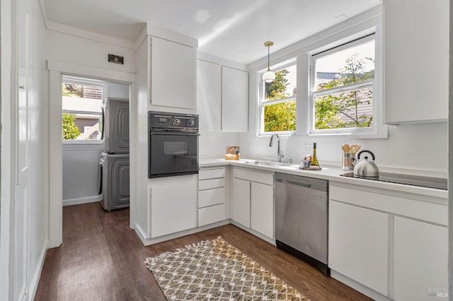 kitchen with black appliances, a sink, stacked washer / dryer, and plenty of natural light