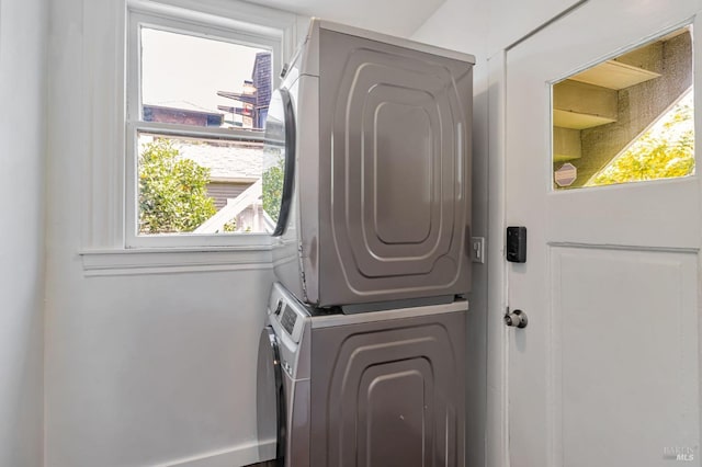 laundry area with stacked washer and clothes dryer, plenty of natural light, and baseboards