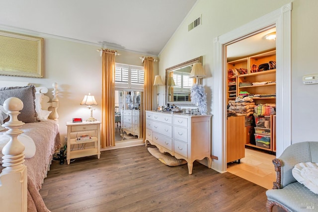bedroom featuring a walk in closet, lofted ceiling, light wood finished floors, and a closet