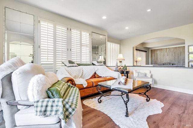 living room with arched walkways, wood finished floors, recessed lighting, and baseboards