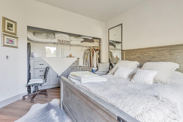 bedroom with wood finished floors, baseboards, and a closet