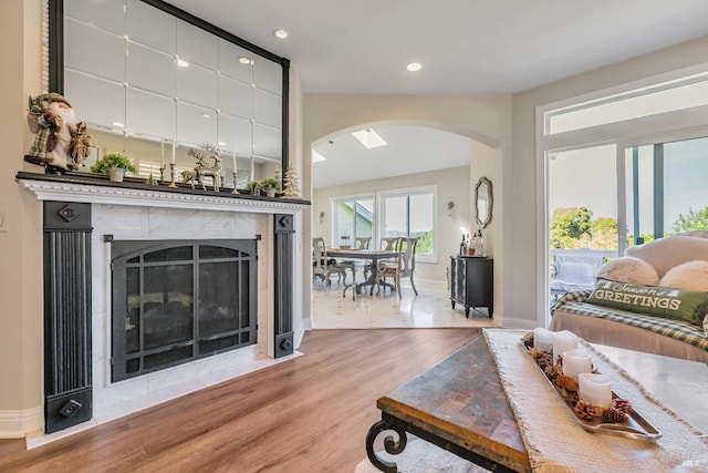 living area with arched walkways, wood finished floors, a fireplace, baseboards, and recessed lighting