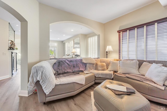 living area with arched walkways, wood finished floors, baseboards, and recessed lighting
