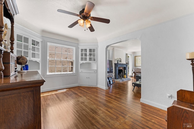 32 Muller St, Vallejo, CA 94590 - living area featuring hardwood / wood-style flooring, a fireplace with raised hearth, baseboards, a ceiling fan, and arched walkways