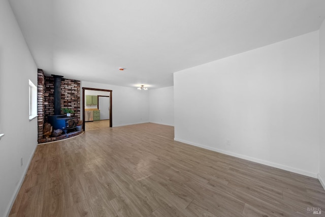 17651 Van Arsdale Rd, Potter Valley, CA 95469 - unfurnished living room featuring a wood stove, wood finished floors, and baseboards