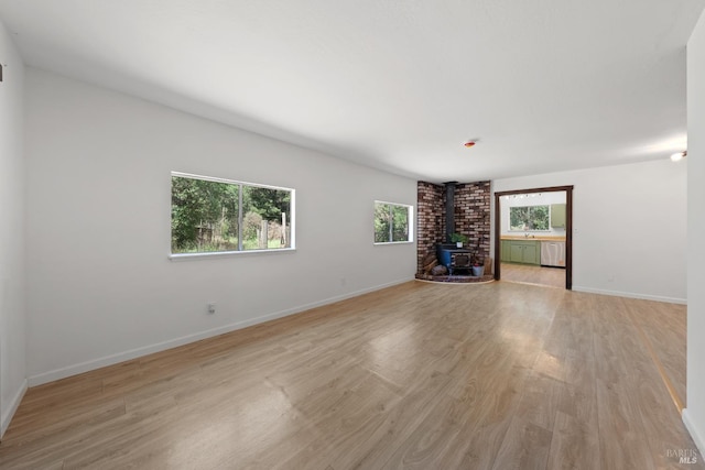 17651 Van Arsdale Rd, Potter Valley, CA 95469 - unfurnished living room with a wood stove, light wood finished floors, and baseboards