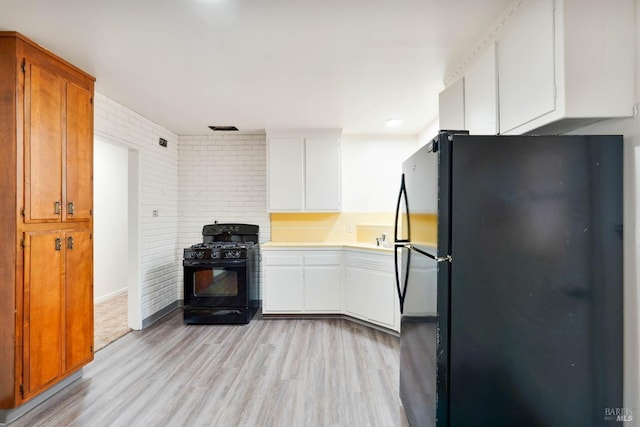 2409 Springs Rd, Vallejo, CA 94591 - kitchen with black appliances, light wood-type flooring, light countertops, white cabinets, and brick wall