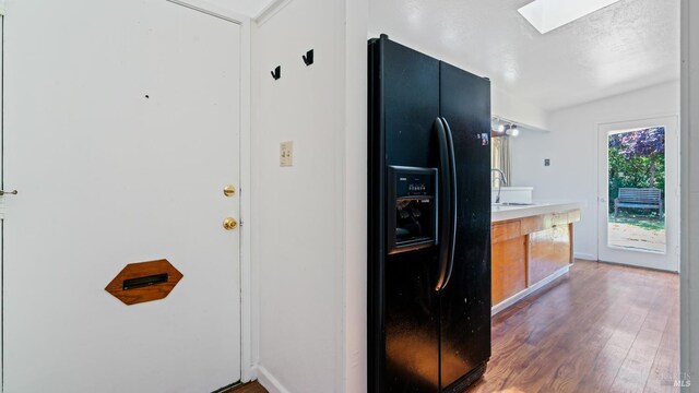 375 Las Colindas Rd, San Rafael, CA 94903 - kitchen with black refrigerator with ice dispenser, a skylight, wood finished floors, light countertops, and a sink